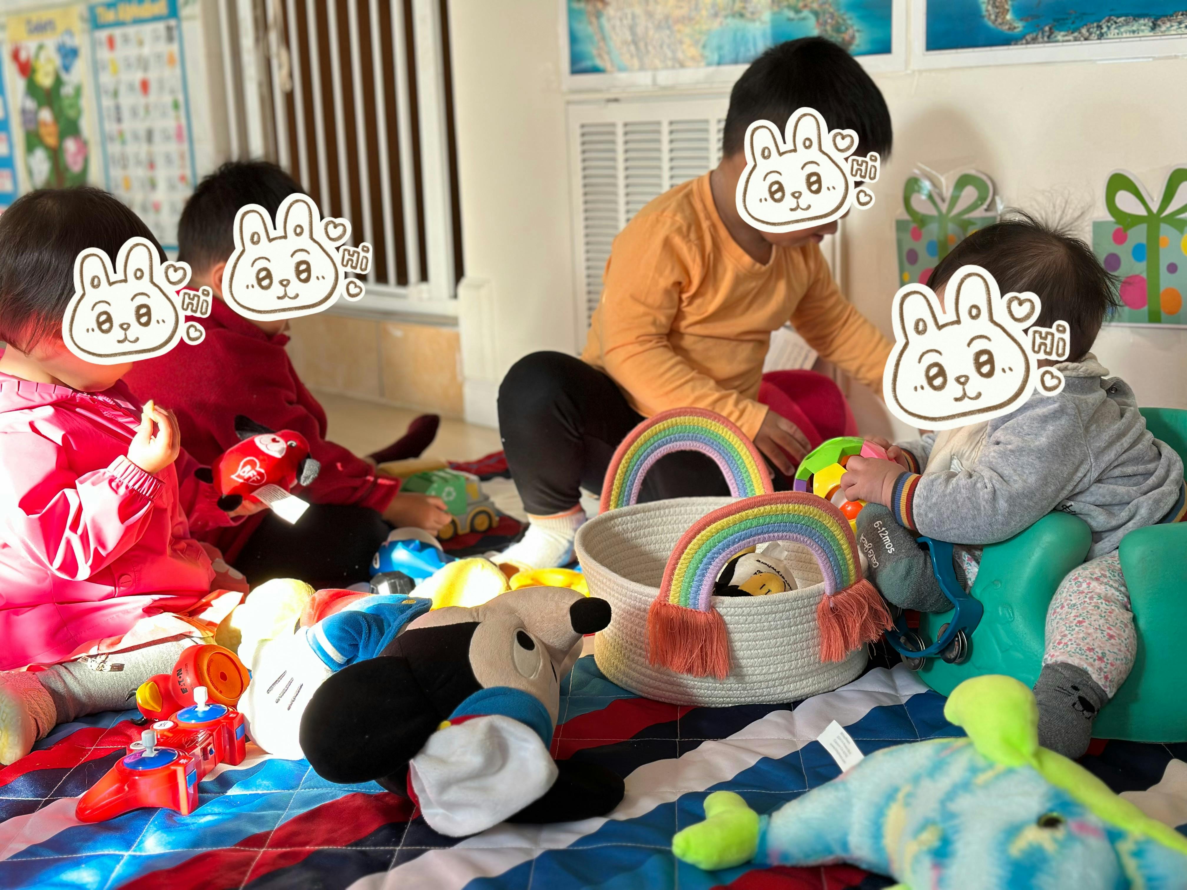 Four children playing with toys on a patterned blanket