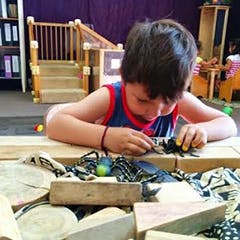Child playing with small objects on a wooden surface