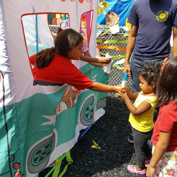 Child in red shirt handing an item to a younger child