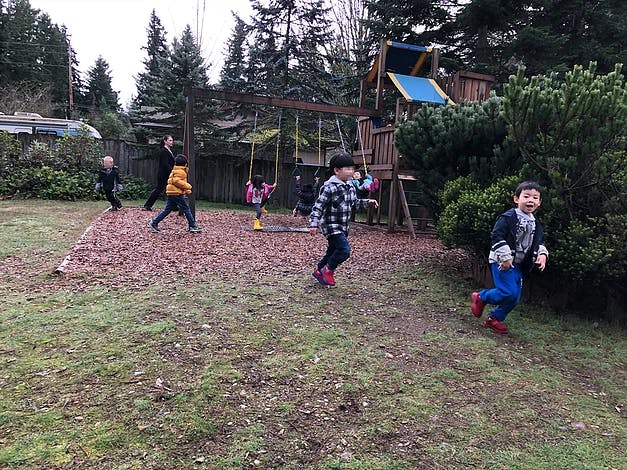 Children running and playing near a playground structure