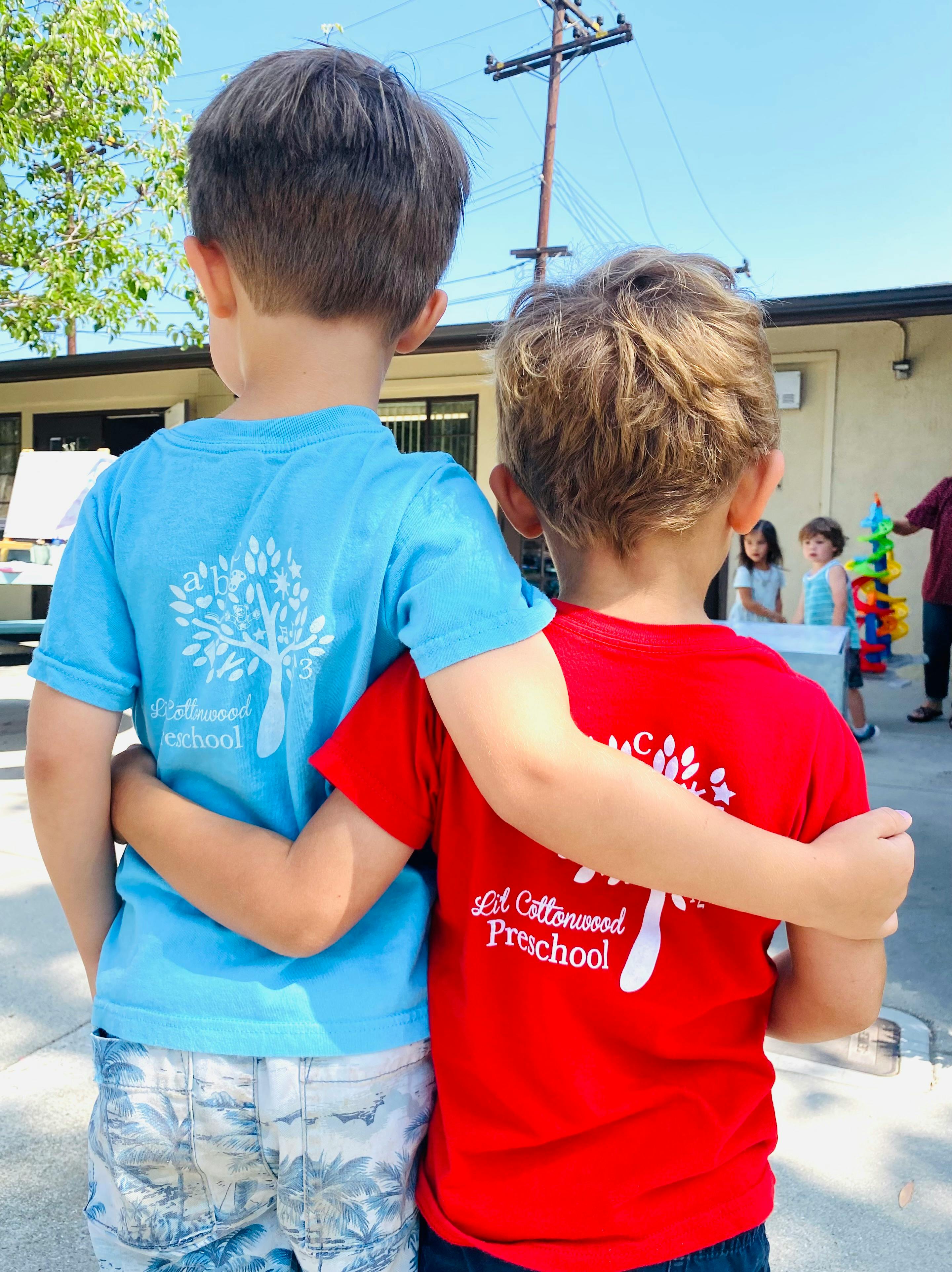 Two children with arms around each other, seen from behind