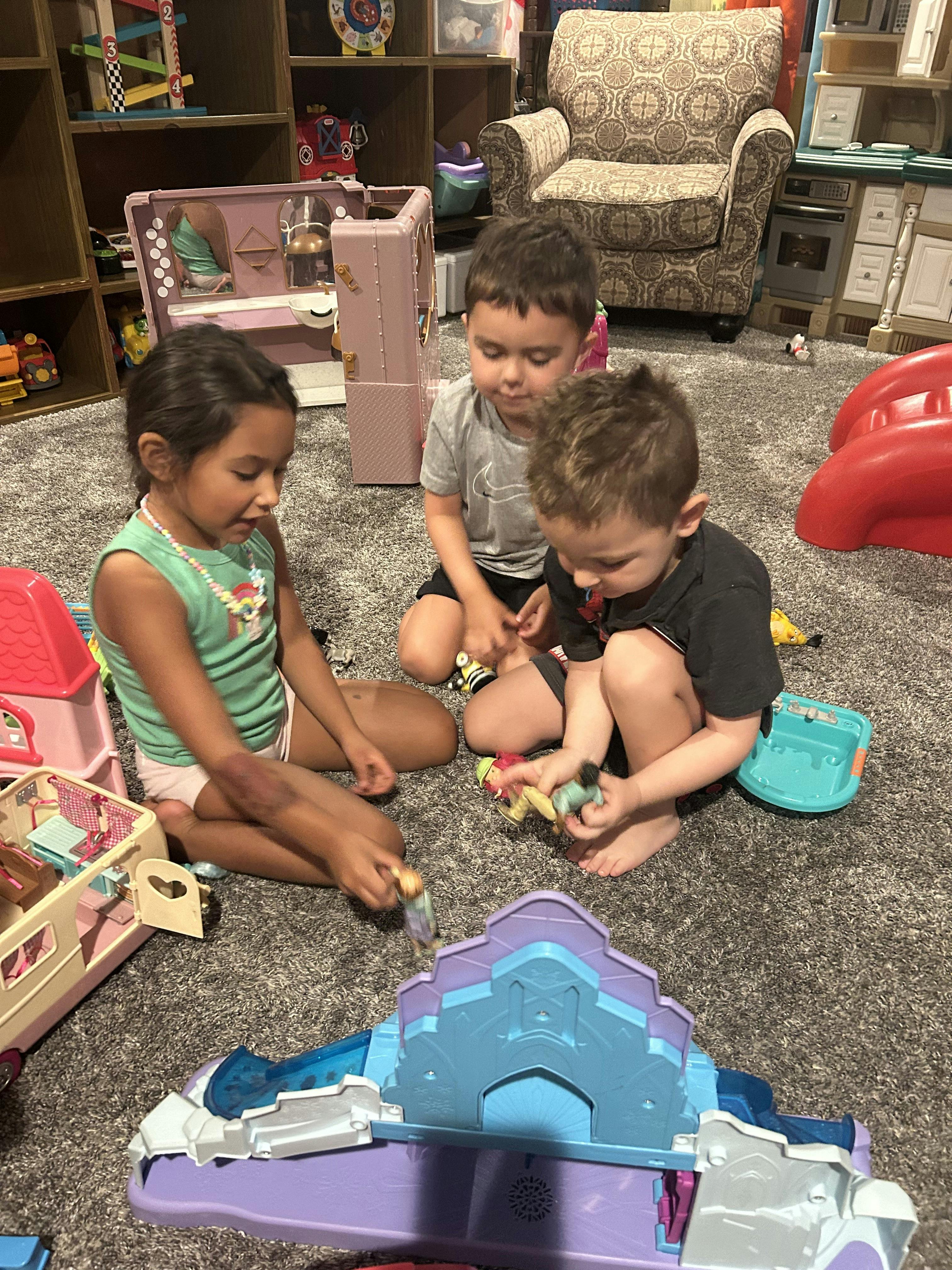 Three children playing with toys on a carpeted floor