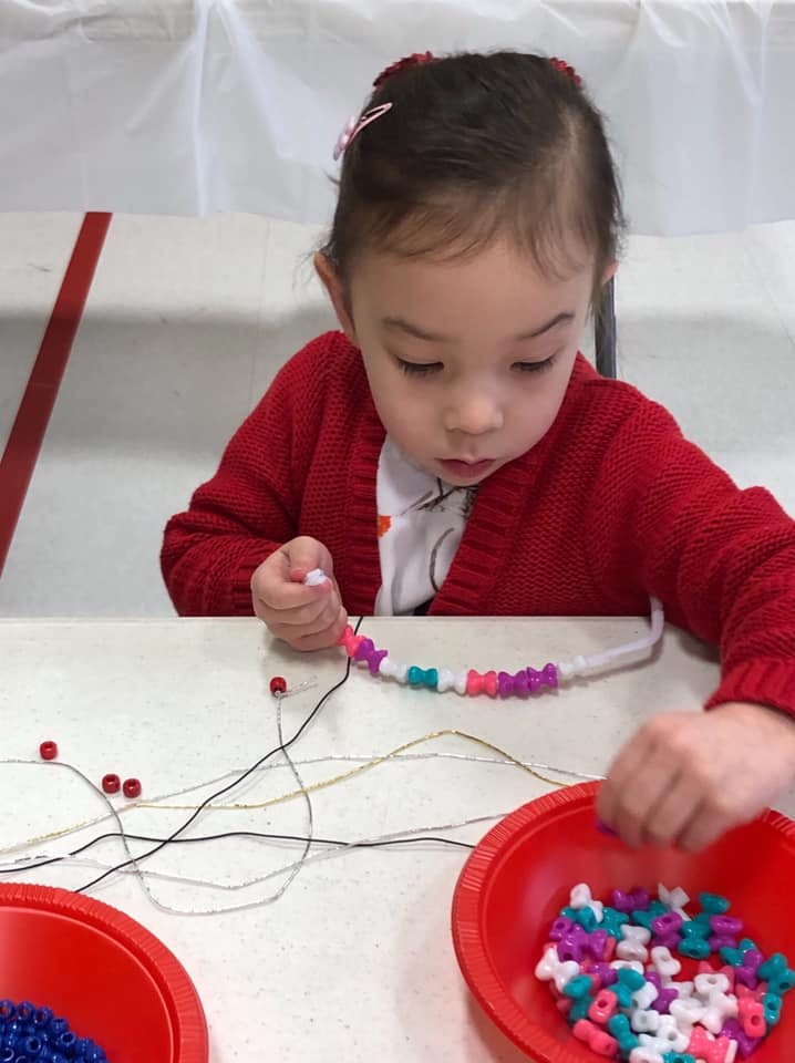 Child stringing beads onto a wire