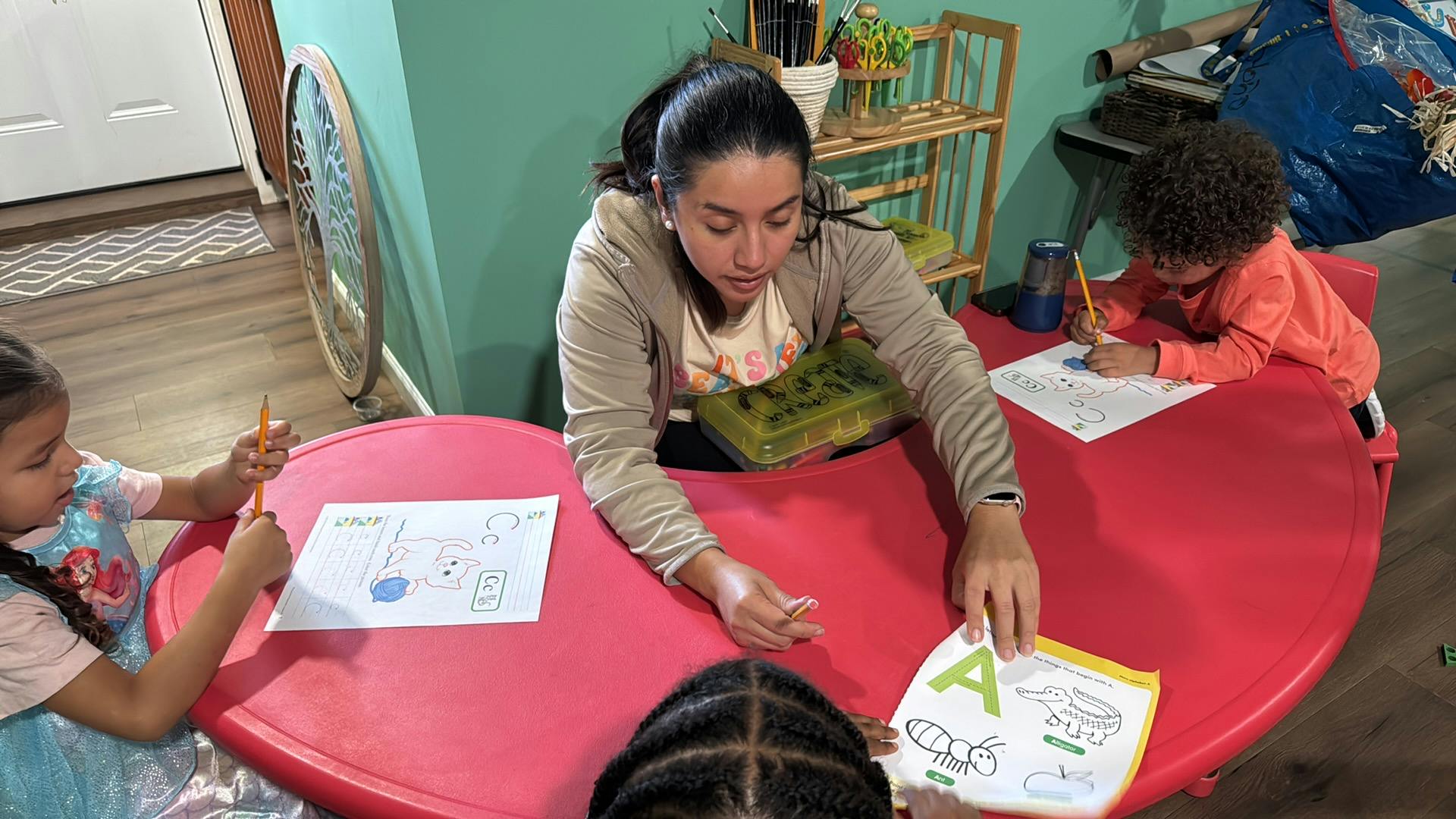 Adult assisting three children with worksheets at a table