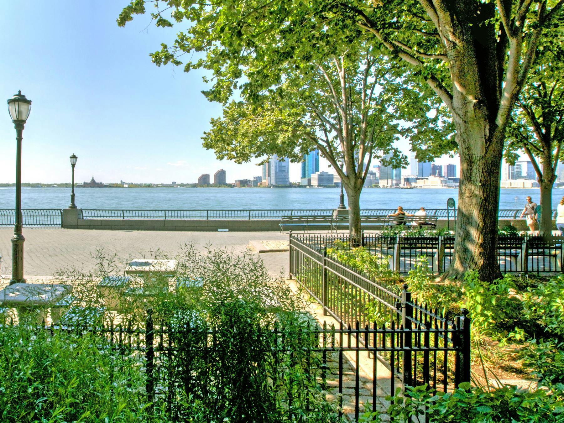 Waterfront park with trees and a city skyline across the water