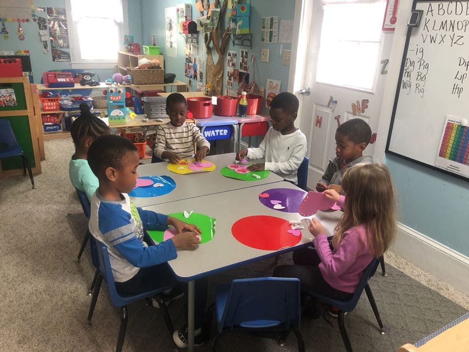 Children sitting at a table with colorful paper cutouts
