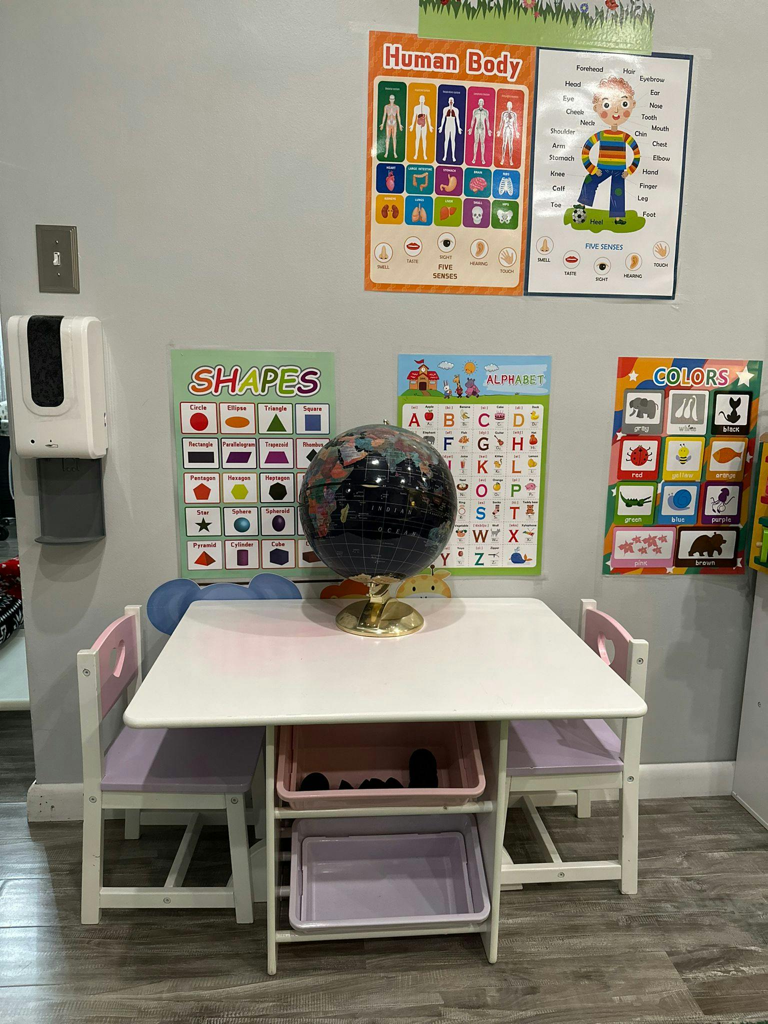 Children's table with chairs, globe, and educational posters on the wall