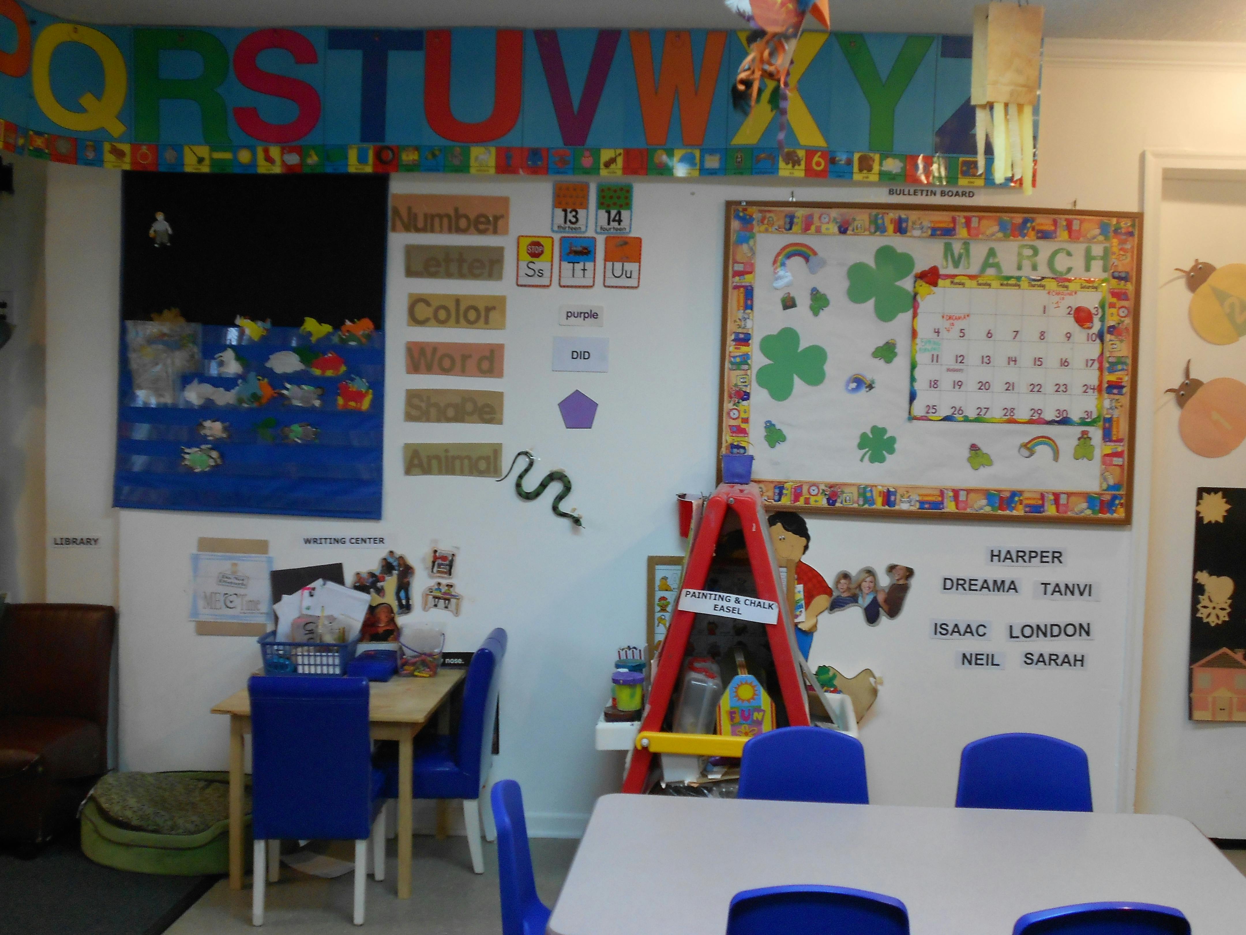 Classroom with tables, chairs, and educational decorations on the walls