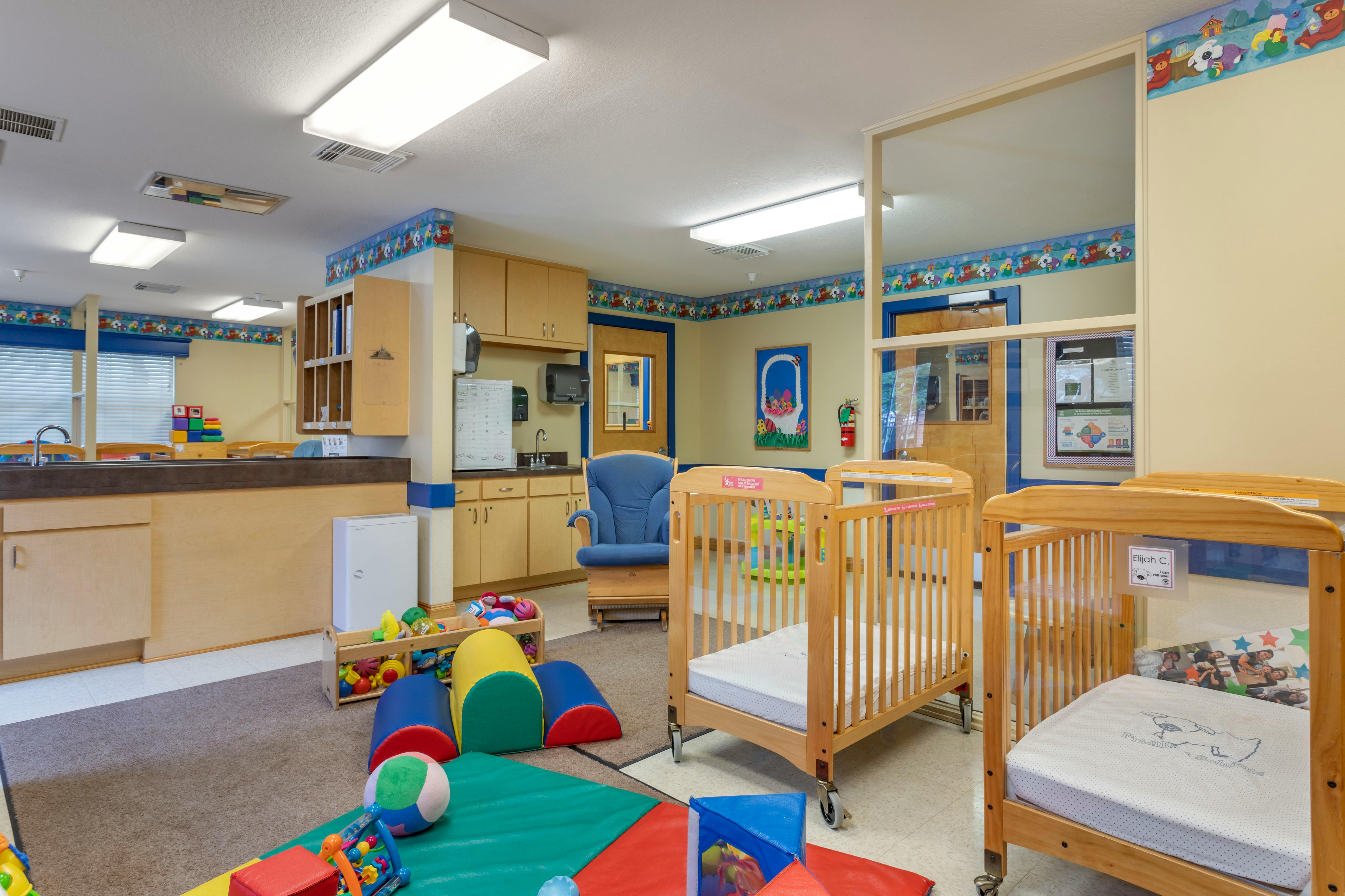 Cribs, infant play mats, and a changing station in a childcare room