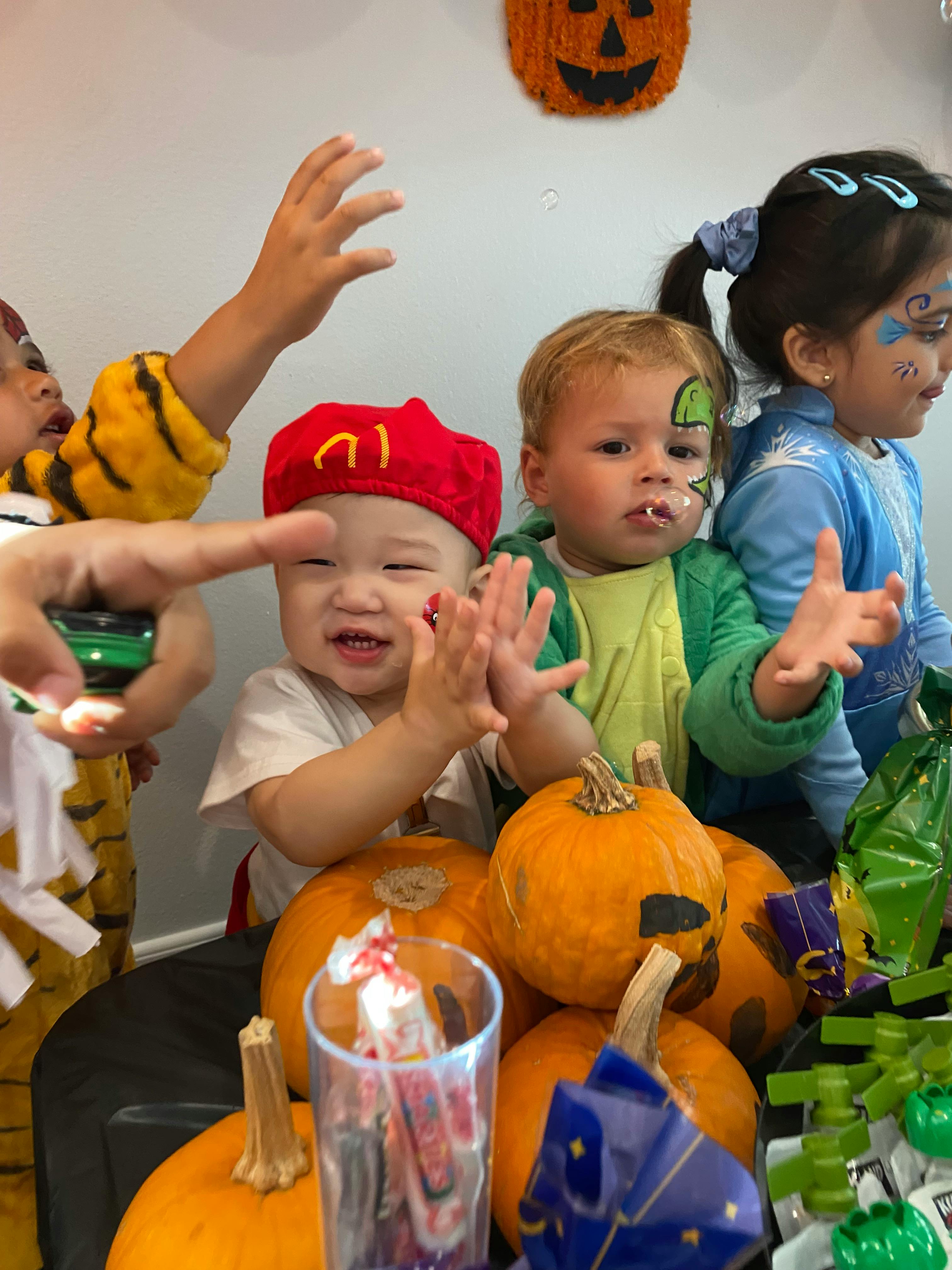 Three children in costume around pumpkins and Halloween candy