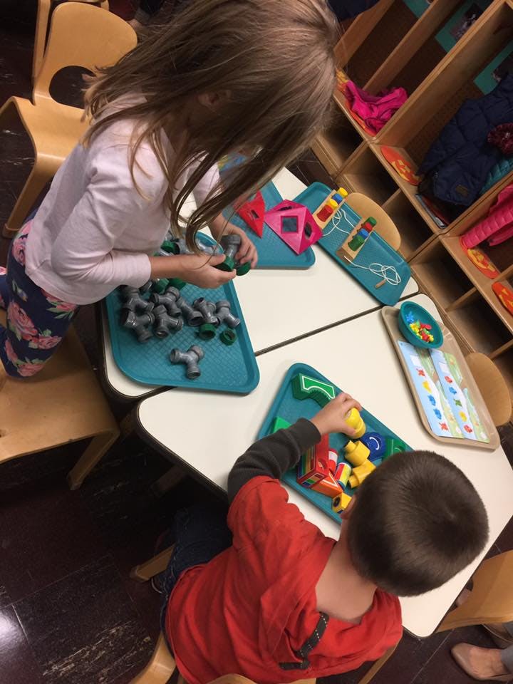 Two children playing with toys at a table
