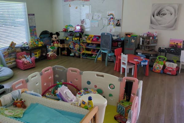 Room filled with children's toys and play equipment, including a crib and playpen