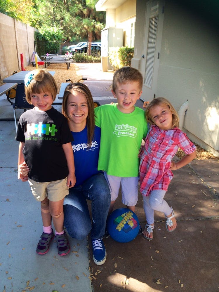 Person kneeling with three children standing around them outdoors