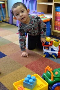 Child on hands and knees on a colorful floor with toys