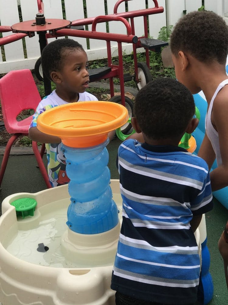 Three children playing with a water table