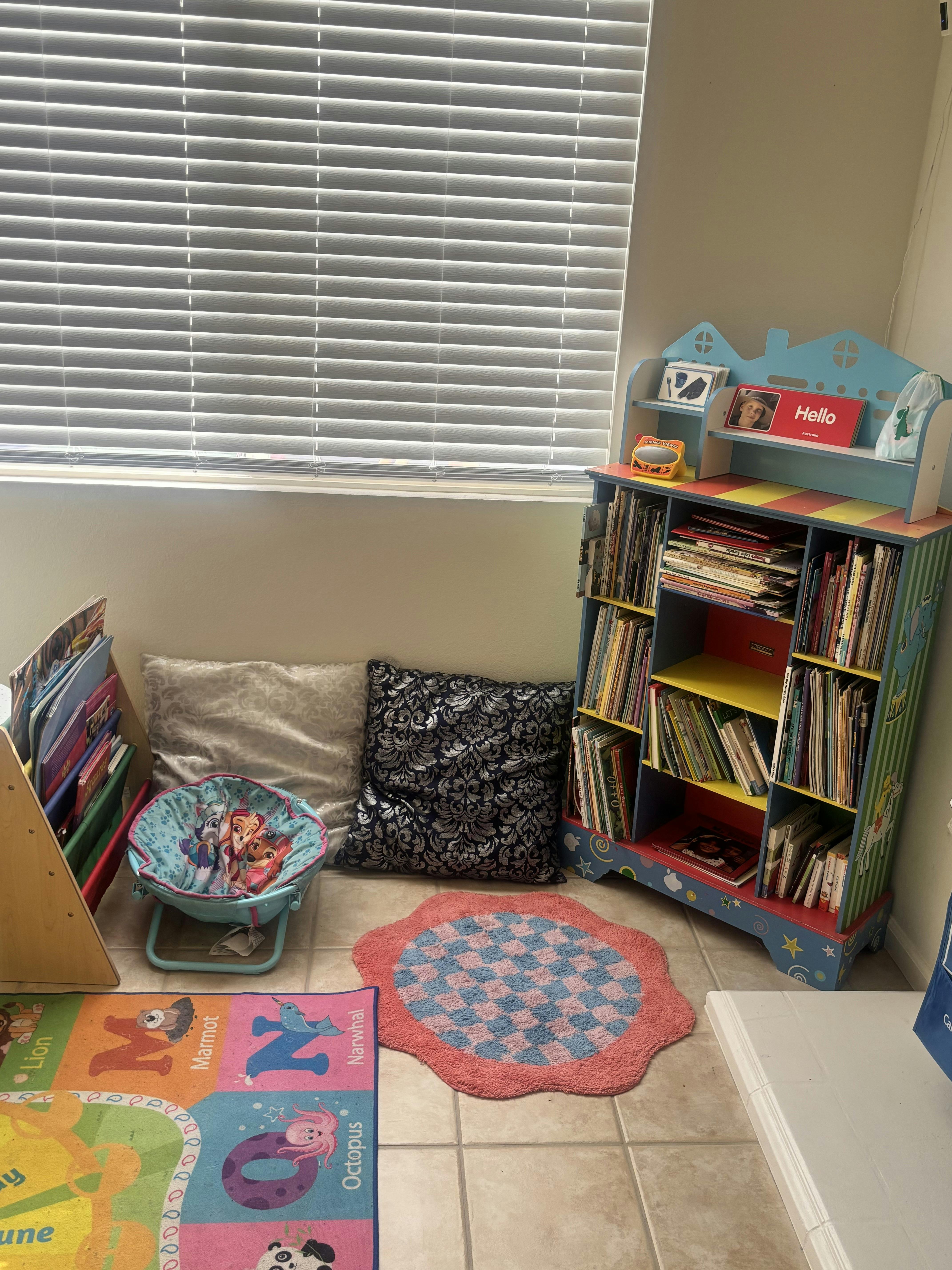 Children's reading nook with a colorful bookshelf, floor mat, and small chair