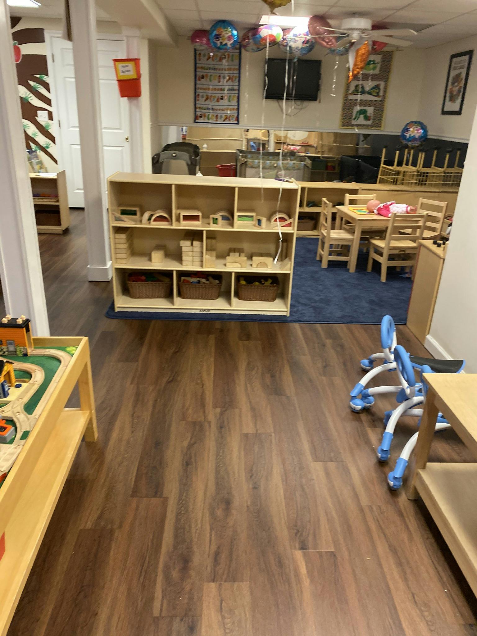 Playroom with wooden shelves, small tables and chairs, and a play train set