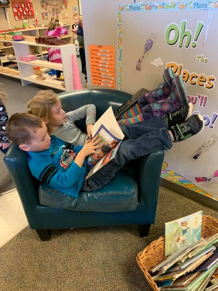 Two children reading a book together in a chair