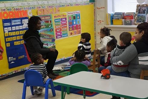 Person reading to a group of children in a classroom