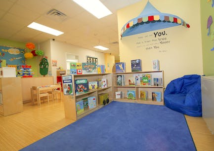 Classroom with bookshelves, blue rug, and small tables