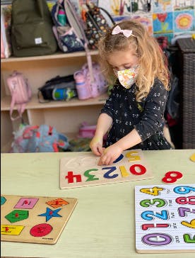 Child in a mask playing with number puzzles