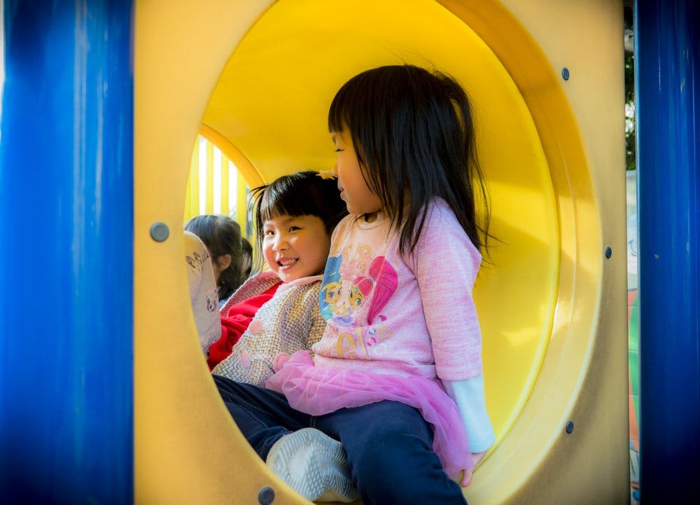 Two children in a yellow play tunnel