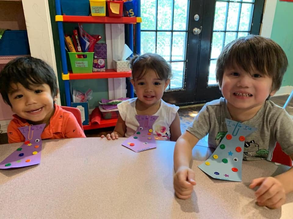 Three children sitting at a table with paper ties