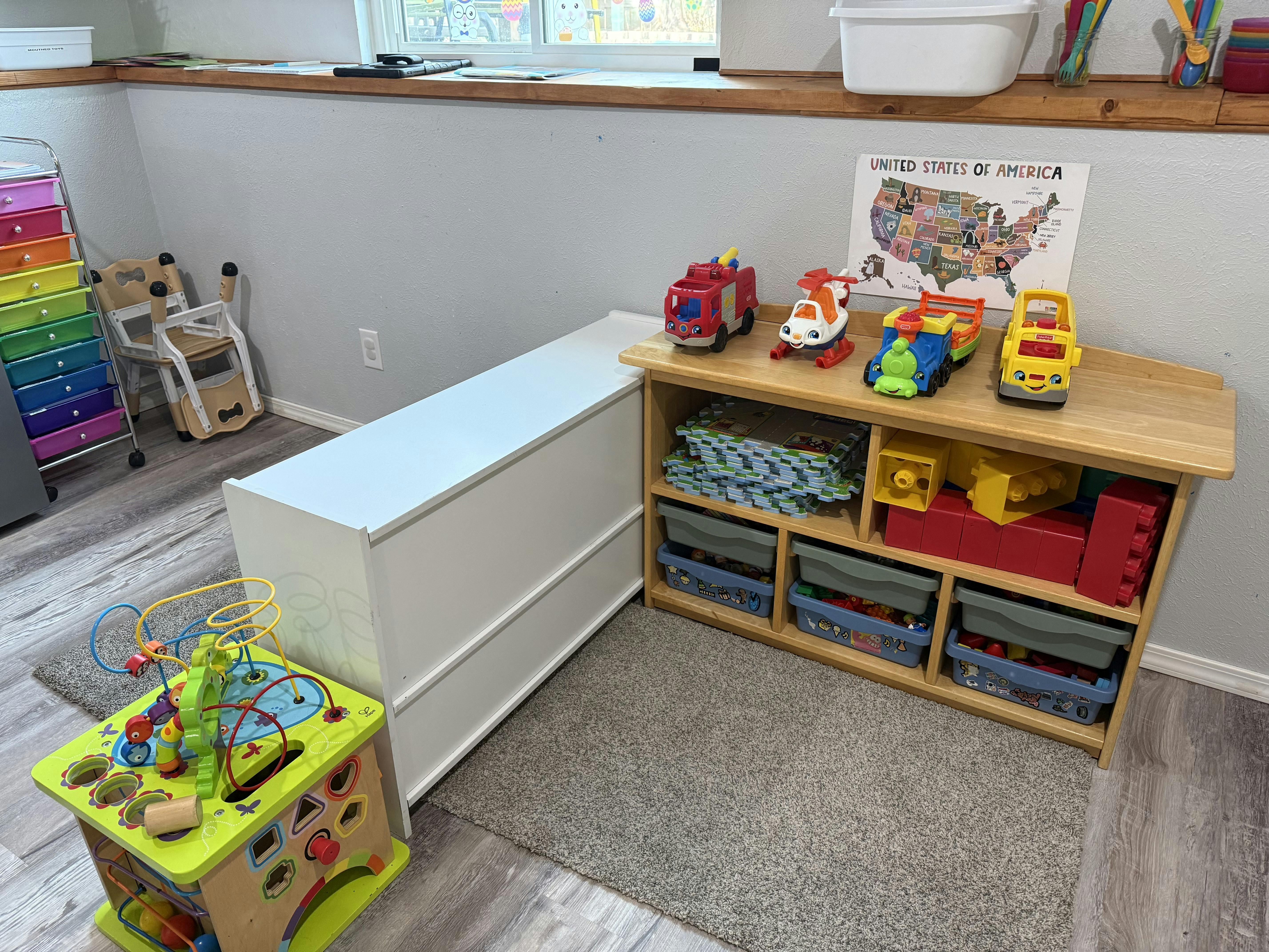 Children's play area with a large activity cube, toy organizer, and a US map poster