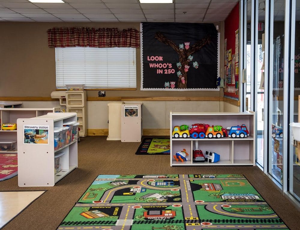 Classroom with toy cars on shelves and a road map rug