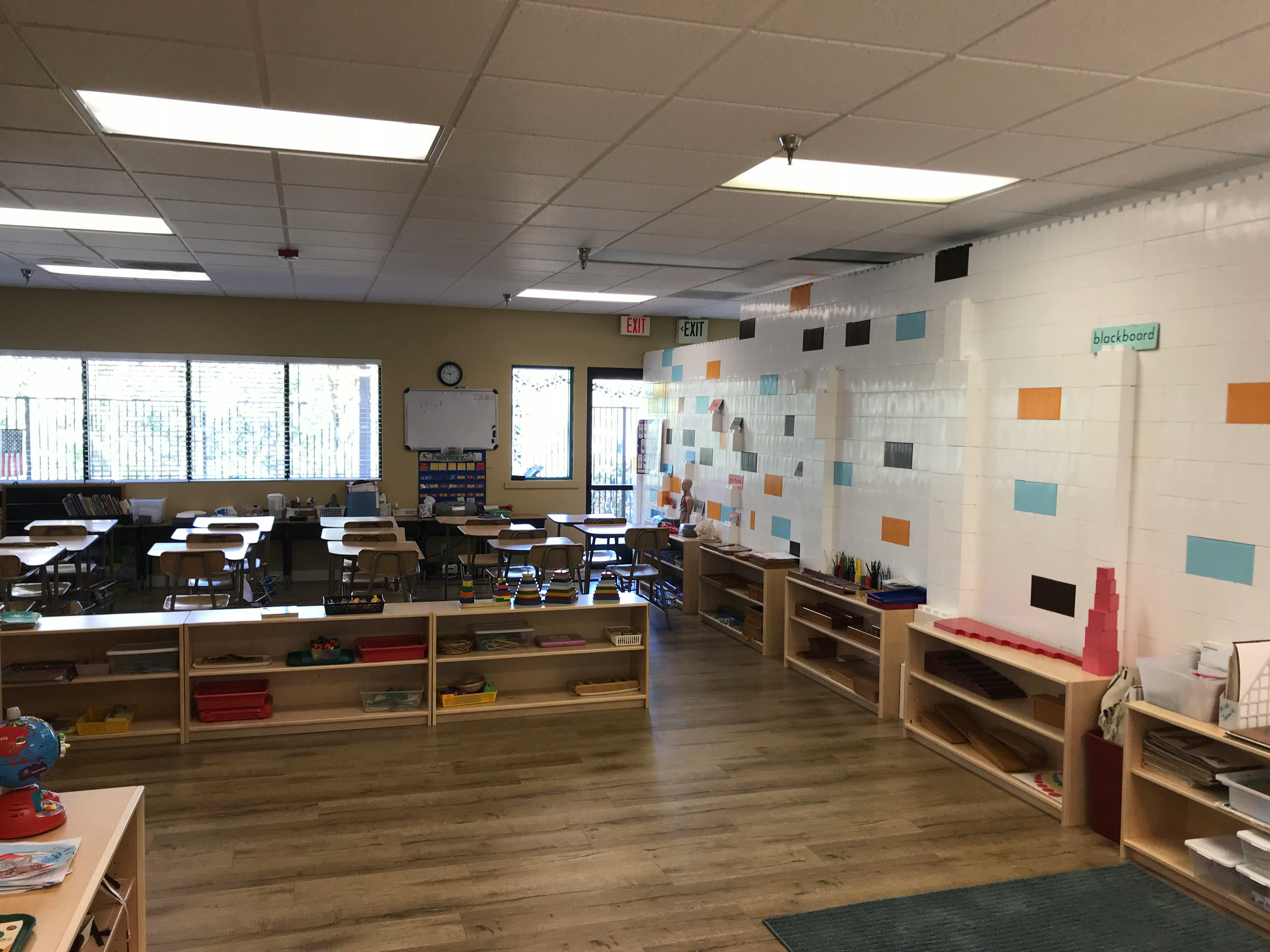 Empty classroom with desks, chairs, and shelves