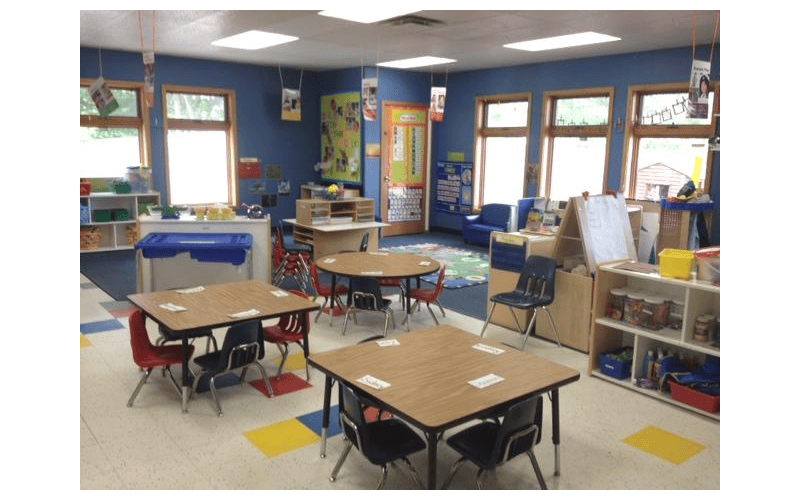 Classroom with small tables and chairs, toys, and learning materials