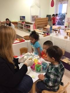 Adult and three children decorating eggs at a table