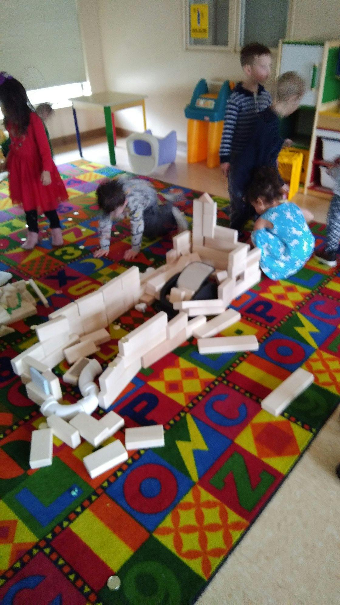 Children playing with wooden blocks on a colorful alphabet rug