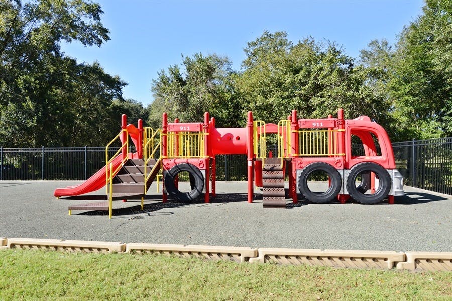 Red fire truck themed playground with slides and climbing structures