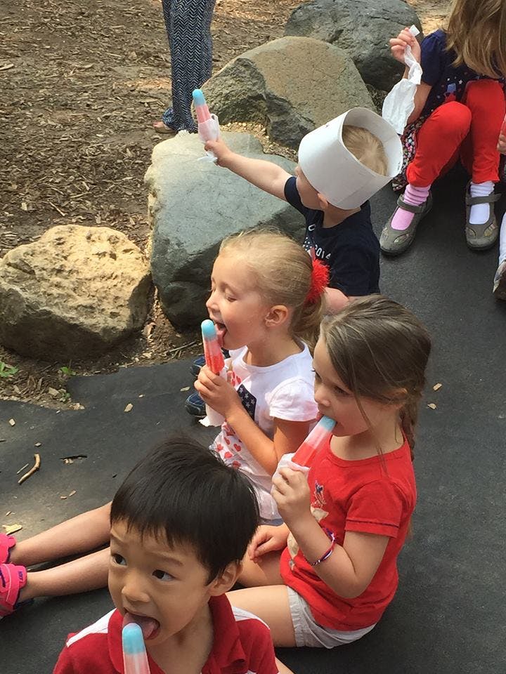 Children sitting on the ground eating popsicles