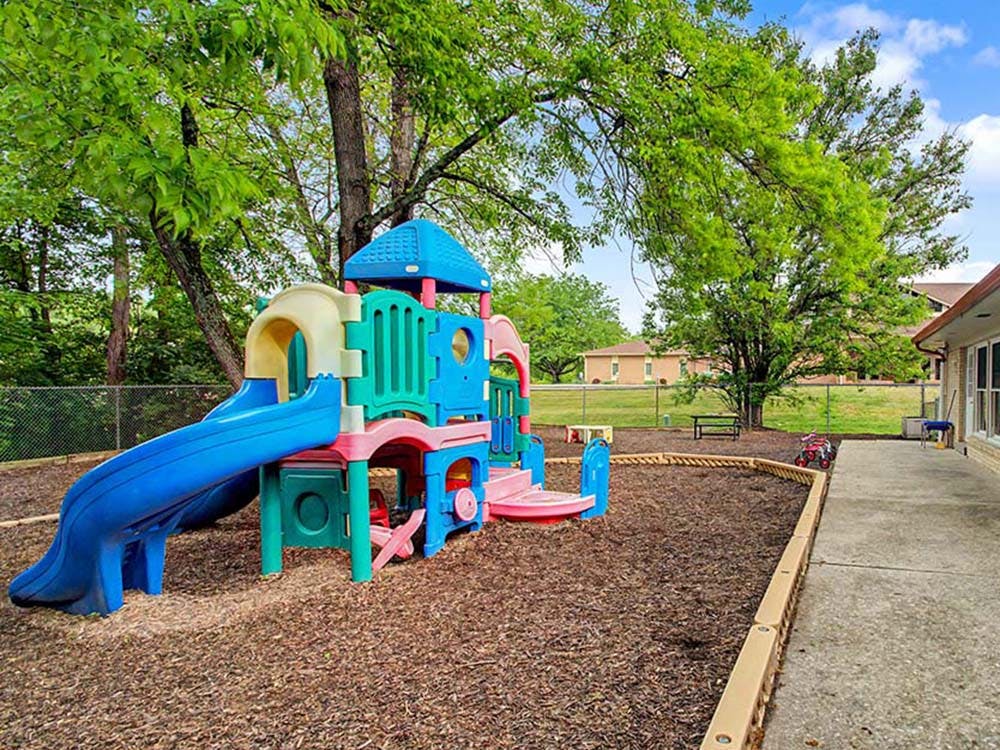 Colorful playground structure with a blue slide in a mulched area