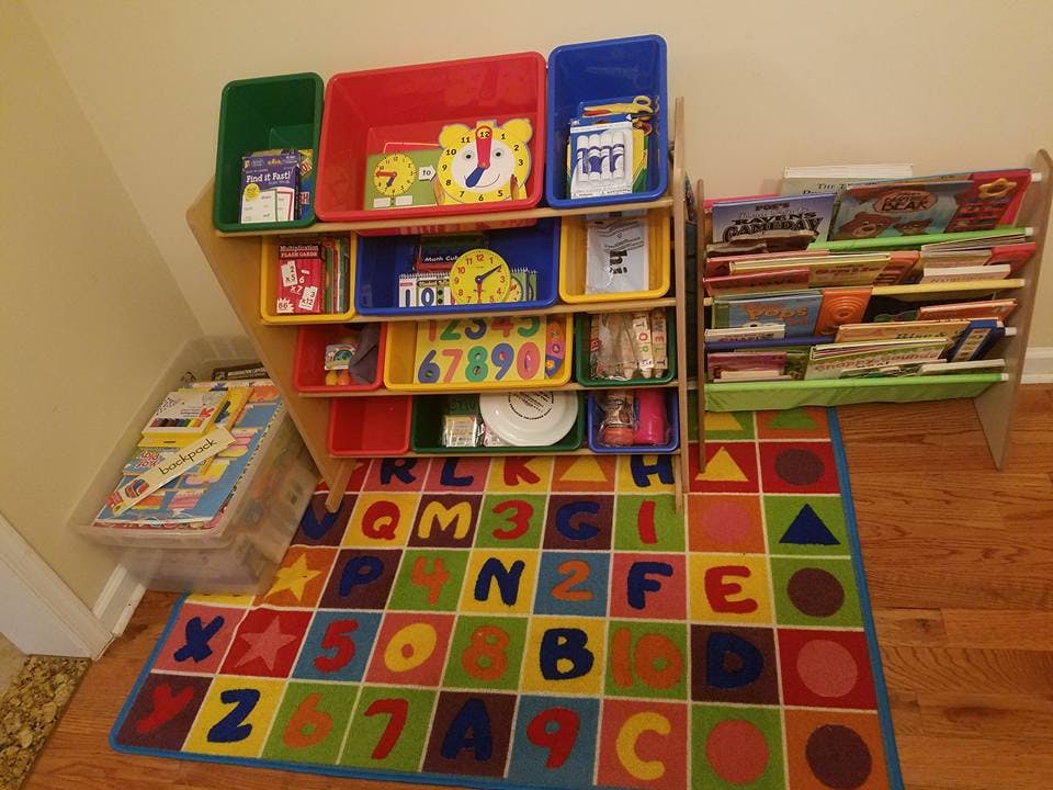 Children's playroom with toy organizer, bookshelf, and alphabet rug