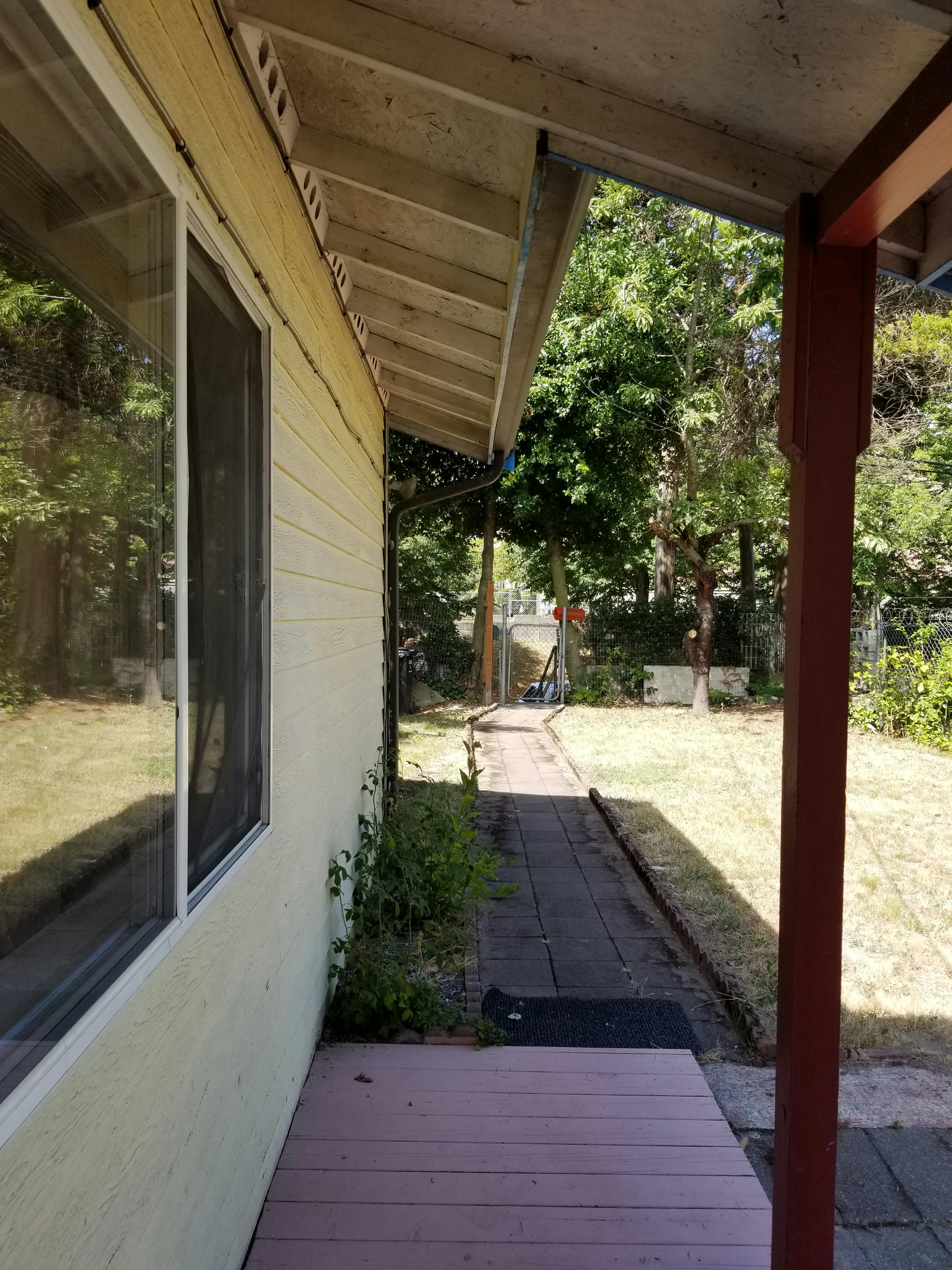 Side of a house with a window and a path leading to a grassy yard