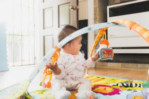 Child playing with a baby gym toy