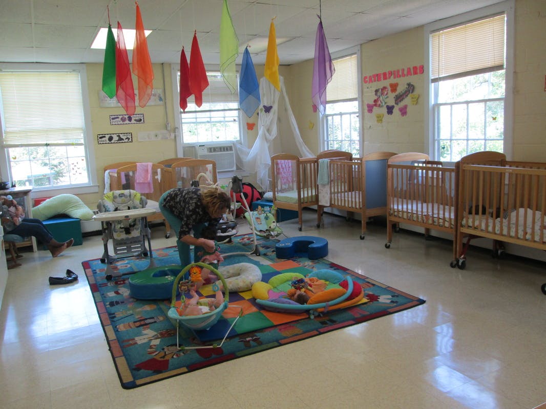 Person interacting with a child in a room with cribs and colorful decorations