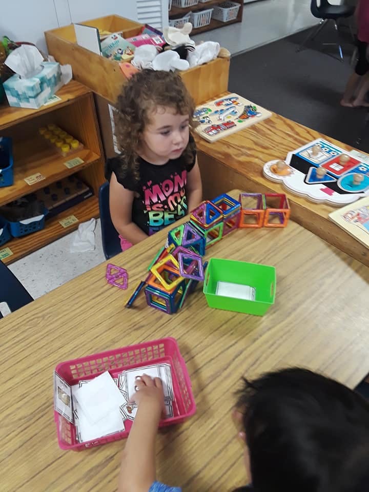 Child sitting at a table with magnetic building blocks