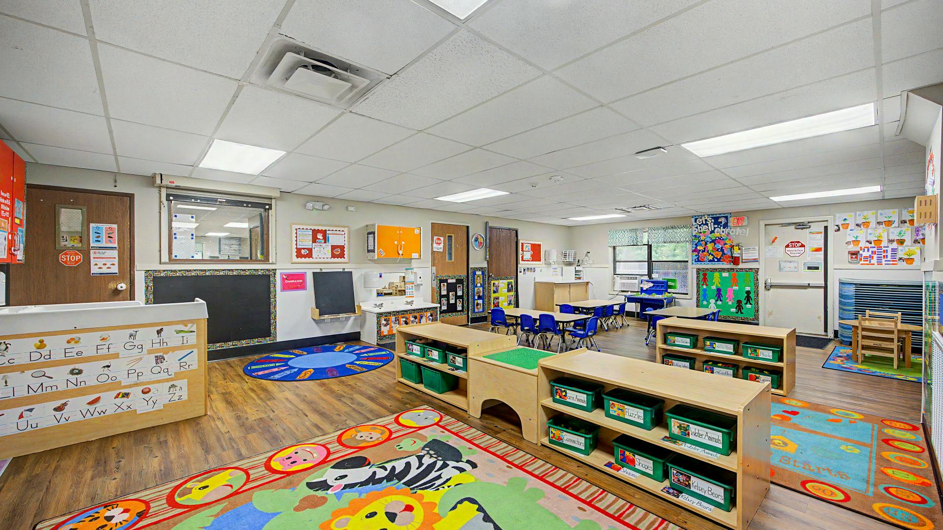 An empty early childhood classroom with colorful rugs and small tables