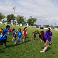 People and children playing on a grassy field