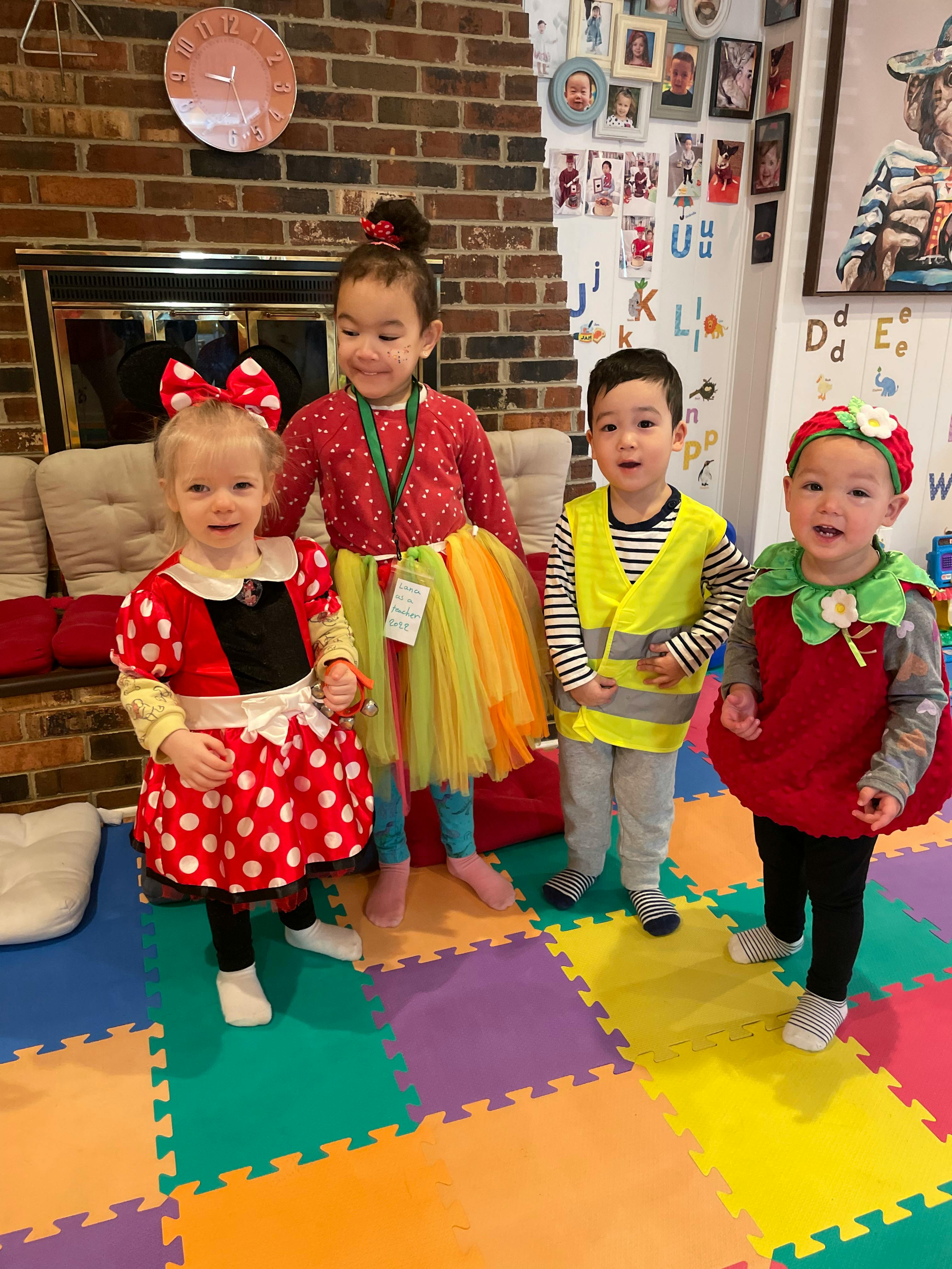 Four children in costumes standing on a colorful mat
