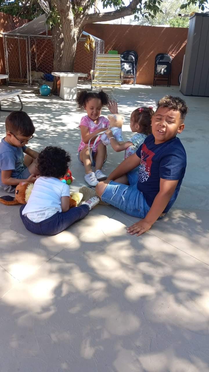 Children sitting on the ground playing with toys outdoors