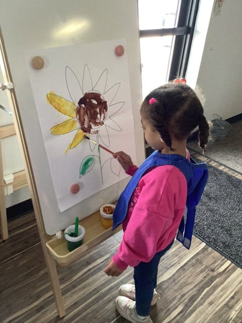 Child painting a sunflower on an easel