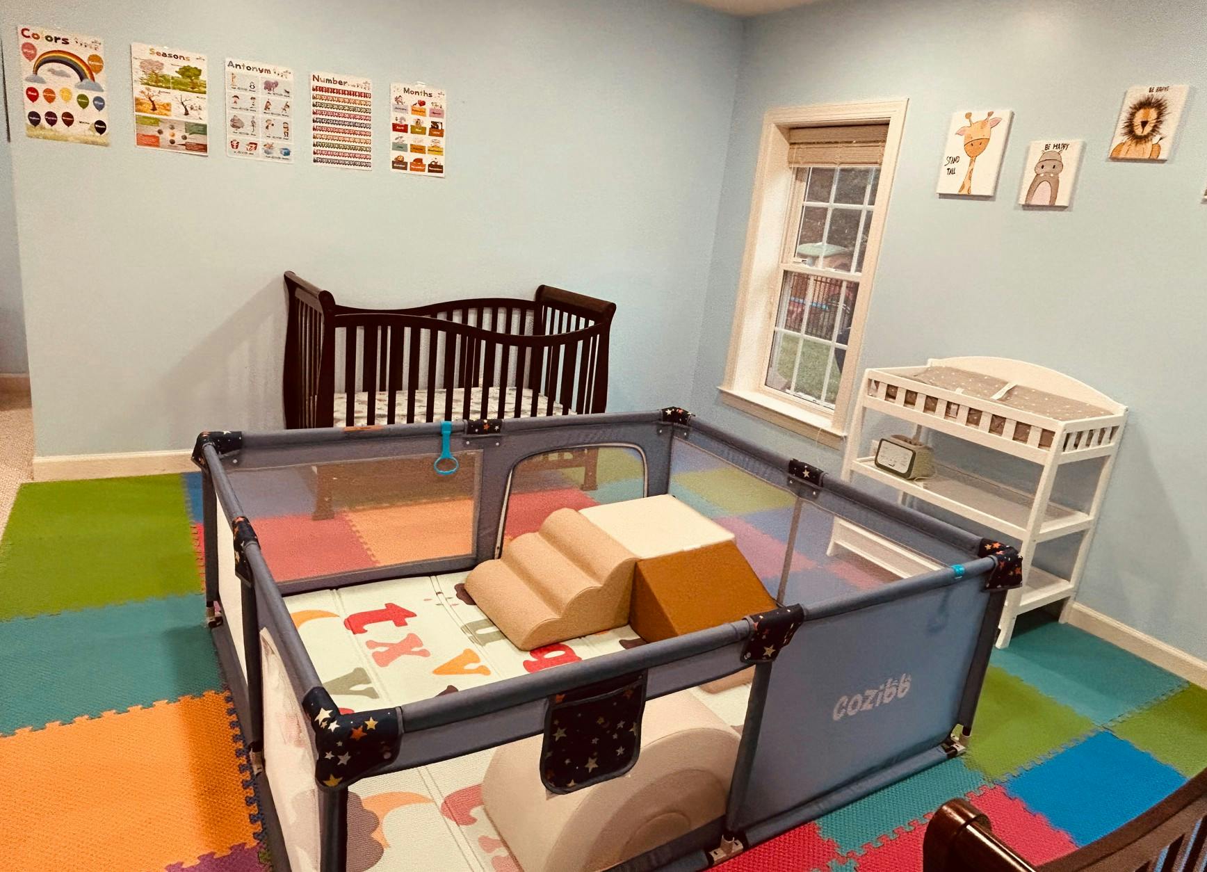 Playpen with soft climbing blocks in a nursery with a crib and changing table