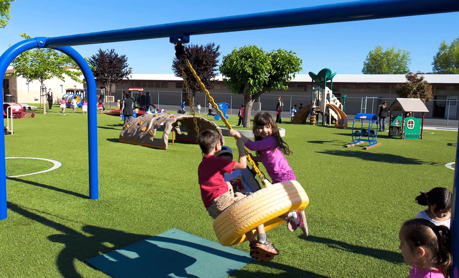 Two children on a tire swing in a playground