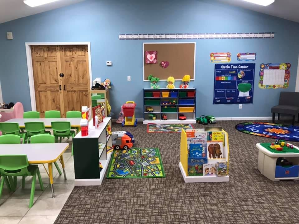 Playroom with small tables and chairs, toys, and educational posters