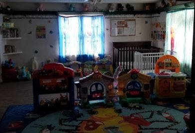 Playroom with toys on a rug and a crib in the background